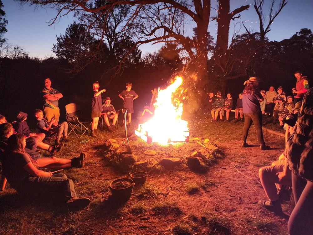 Scouts sitting around a large campfire at dusk at Berrima Scout Camp